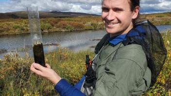 A project member holding a soil core from an Arctic wetland. 